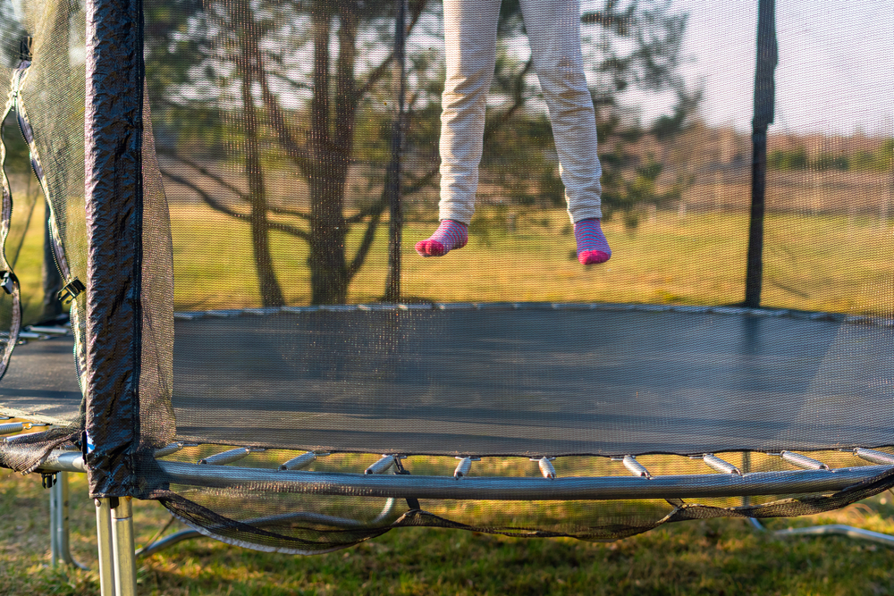 child jumping on a trampoline in a yard