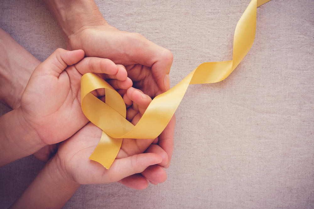 parent and child holding a gold ribbon for children