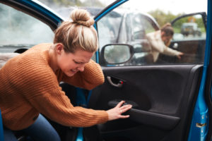 woman holding her neck getting out of the car