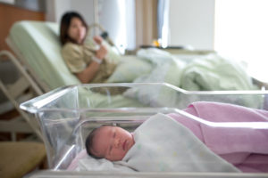 baby in a hospital bed with mother in background